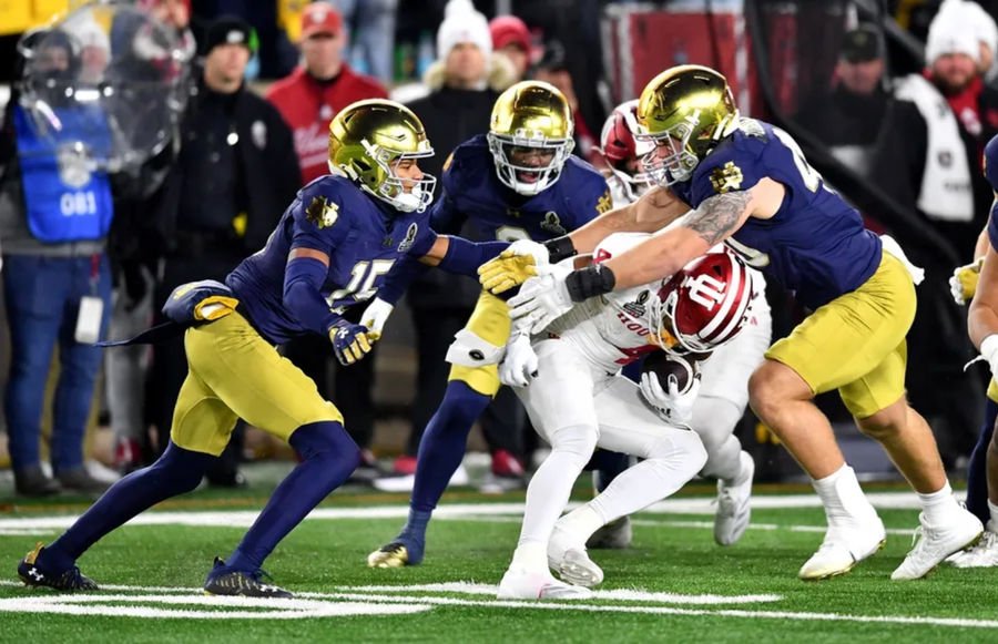 Dec 20, 2024; Notre Dame, Indiana, USA; Notre Dame Fighting Irish defensive lineman Joshua Burnham (40) and cornerback Leonard Moore (15) tackle Indiana Hoosiers wide receiver Myles Price (4) during the third quarter at Notre Dame Stadium. Mandatory Credit: Matt Cashore-Imagn Images