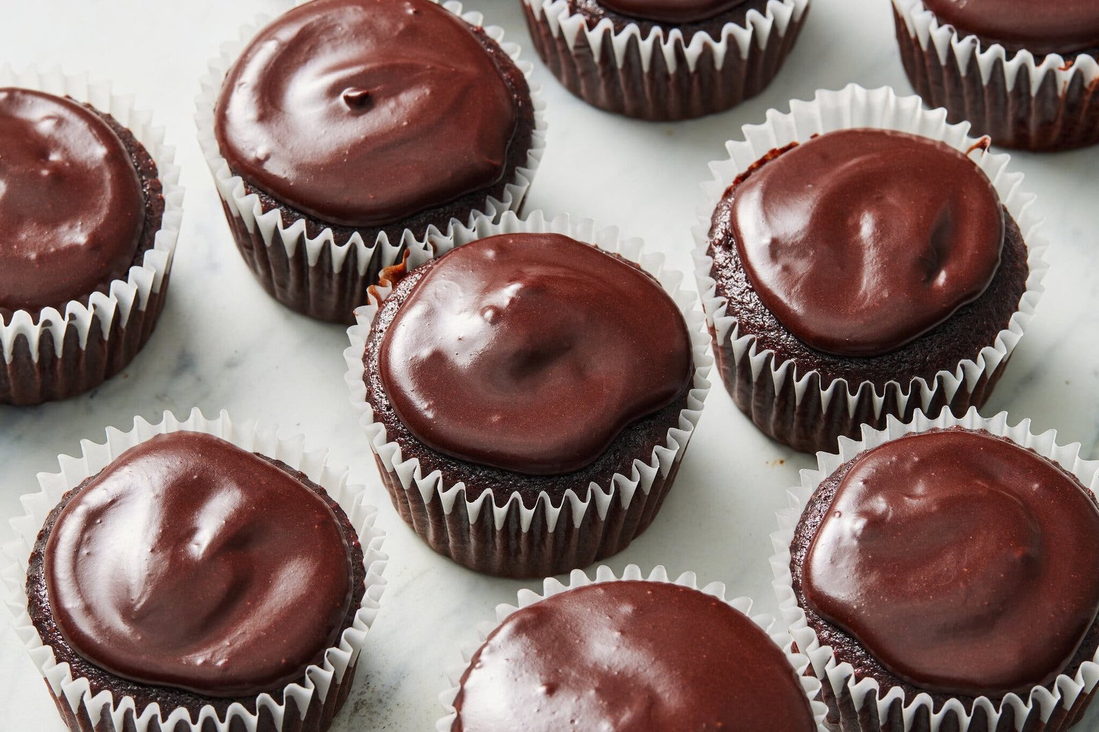 An overhead image of chocolate cupcakes topped with chocolate frosting.